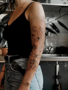 a woman with a flower tattoo on her arm in a kitchen next to a counter