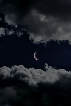 the moon is seen through dark clouds on a cloudy day