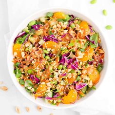 a white bowl filled with oranges, cabbage and nuts