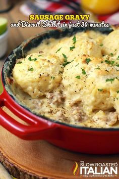 a red skillet filled with mashed potatoes on top of a wooden table next to sliced oranges