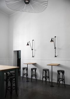 an instagram photo of two tables and stools in a room with white walls