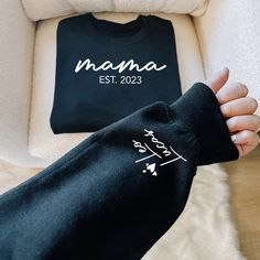 "Custom Mama Sweatshirt with Date and Childs Name on Sleeve, New Mom, Personalized Mom Hoodie, Minimalist Mom Sweater, Birthday Gift for Mom ----------- How to Order Your Custom Design T-shirt ---------- * Choose your t-shirt color * Choose your size * PLEASE make sure all your order's steps Please type: Only name(s) on the sleeve (For multiple names, please list commas between them) And please type Est. Year -The text on the chest and the hearts on the sleeve will be automatically added -Names are printed on one sleeve only For Example: Leo, Lucas Est. 2023 ---------- Product ---------- * 4.2 oz., 100% airlume combed and ringspun cotton, 32 singles * 32 singles Athletic Heather and Black Heather are 90/10 airlume combed and ringspun cotton/polyester Ash is 99/1 airlume combed and ringspun Black Hooded Sweatshirt Gift, Black Hooded Sweatshirt As Gift, Birthday Long Sleeve Hoodie With Letter Print, Birthday Letter Print Long Sleeve Hoodie, Long Sleeve Hoodie With Letter Print For Birthday, Black Long Sleeve Sweatshirt With Name Print, Family Matching Black Sweatshirt For Winter, Family Matching Black Winter Sweatshirt, Black Long Sleeve Sweatshirt With Custom Text