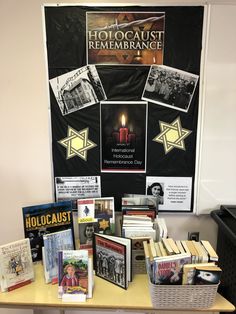 a table topped with books and pictures next to a sign that says holoclust remembrance