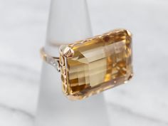 What a beauty! The centerpiece of this lushly shaded ring is the bright, golden-hued citrine that we've set at the center. Although filled with neutral tones that will go with anything, this amazing mounting is filled with color and light sparkling from the twinkling diamonds!Metal: 18K Yellow and White GoldGem: Citrine 27.20 Carats Gem Measurements: 21.7 x 15.8 mm, Emerald CutAccents: 6 Diamonds totaling .08 Carats, SI-I in Clarity, G-I in ColorRing Size: 5.75 Diamond Cocktail Ring, Color And Light, Filigree Pendant, Diamond Cocktail Rings, Rose Gold Band, White Gold Band, Diamond Drops, Vintage Turquoise, Color Ring