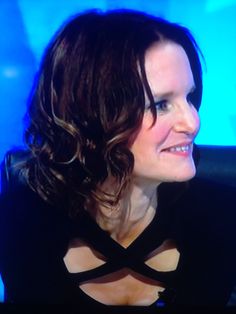 a woman sitting in front of a blue screen with her eyes closed and wearing a black dress