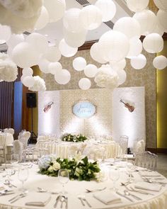 a banquet room with round tables and white decorations