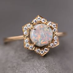 an opal and diamond ring on a gray surface