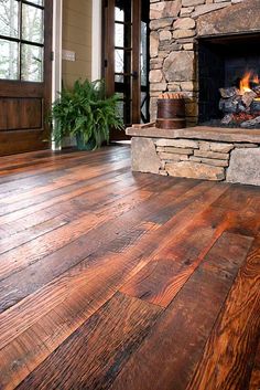 an image of a living room with wood flooring and stone fireplace in the center