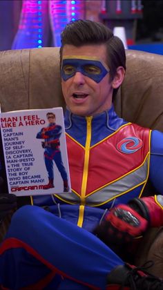 a man in a blue and red costume is reading a book with his face painted like a superhero