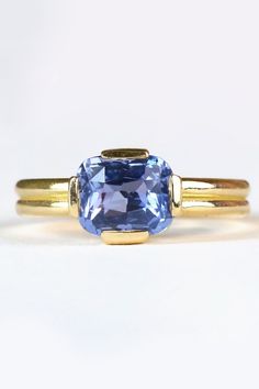 two gold rings with an oval tanzante and blue topazte in the center