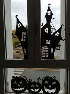 two halloween pumpkins cut out of paper sitting in front of a window