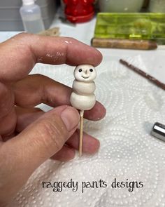 a hand holding a small wooden stick with a smiling face on it