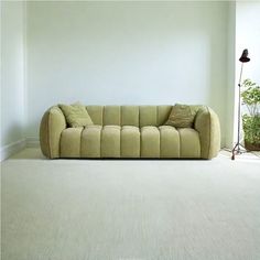 a couch sitting in the middle of a living room next to a potted plant