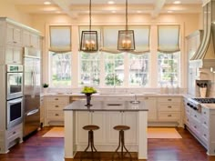 a large kitchen with white cabinets and an island in the middle, along with two stools