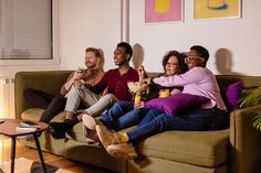 four people sitting on a couch drinking beverages