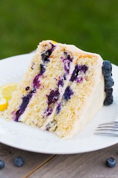 a slice of blueberry cake on a white plate with a fork next to it