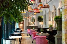 the interior of a restaurant with colorful chairs and tables, potted plants on either side