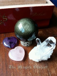 three different colored stones sitting on top of a wooden table next to a book and vase