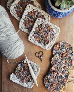 crocheted coasters and yarn on a wooden table with scissors, needles and plant