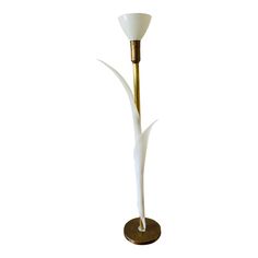 a white and gold floor lamp on a metal base with a glass shade in the middle