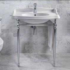 a white sink sitting next to a toilet in a bathroom with marble walls and floor