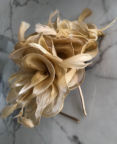 A striking large light gold coloured Fascinator. A gorgeous full flowing design, with shimmering folds of material delicately centred on a gold base. Finished by delicate feather detailing in the same shade makes this Fascinator hat a beautiful addition to any outfit. This piece sits firmly on the head with a co-ordinating satin covered headband. Fascinator measures approx 30cm. Our timeless pieces are perfect for any special occasion from Weddings to The Kentucky Derby and Summer Garden Parties! We offer ready to wear pieces in a variety of styles and colour! However if you want to make your piece unique, we can customise any piece with additional feathers and make it your own! Similarly most fascinators can be created on a comb, headband or clip, whichever you would prefer! If you're loo Elegant Feathered Fascinator For Party, Elegant Feather Fascinator For Party, Feather Fascinator For Royal Ascot, Royal Ascot Headband Fascinator For Event, Royal Ascot Headband Fascinator, Royal Ascot Event Headband Fascinator, Gold Evening Hat For Spring, Gold Mini Hat For Evening In Spring, Gold Mini Hat For Spring Evening