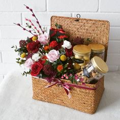 a basket filled with lots of different types of flowers next to a white brick wall