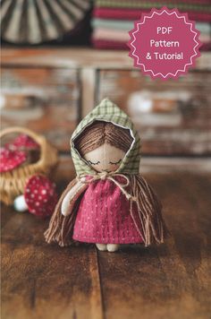 the doll is wearing a pink dress with a hood on it's head and holding a