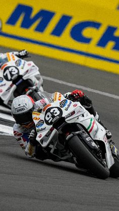 two people racing motorcycles on a race track