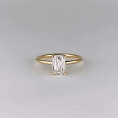 a yellow gold ring with an emerald cut diamond