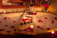 a bath tub with candles and rose petals on it