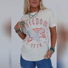 Everyone needs their go - to graphic tee and the Freedom Eagle Graphic Tee is the perfect essential to your boho closet! Comfortable, mineral - washed, Cotton tee shirt fabric Relaxed and loose tee shirt silhouette Classic crew neckline and loose short sleeves So CUTE Distressed Eagle with American Flag and 'Freedom 1776' graphic Pair with: Dora Low Back Seamless Bralette, Straight Arrow Jeans, and Sparrows Song Necklace *Due to lighting and differences in monitors, actual colors may vary slightly from what appears online. Model is 5'8" and wearing a size Small. Approximate measurements are as follows: SMALL: Bust: 34", Waist: 36"", Hip: 36", Length: 27", Sleeve length: 7" MEDIUM: Bust: 38", Waist: 40", Hip: 40", Length: 28 1/2", Sleeve length: 8" LARGE: Bust: 42", Waist: 44", Hip: 44", Le Eagle With American Flag, Boho Closet, Eagle Graphic Tee, Boho Essentials, Shirt Silhouette, Bralette Outfit, Eagle Graphic, Patriotic Shirt, Loose Tees