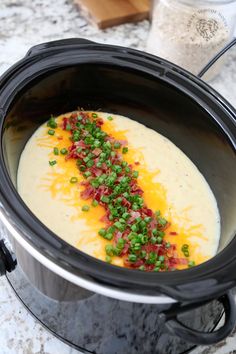 a crock pot filled with soup and garnished with green onions