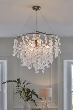 a chandelier hanging from the ceiling over a table with vases and flowers