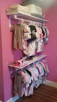 there is a rack with clothes on it in the corner next to a pink wall