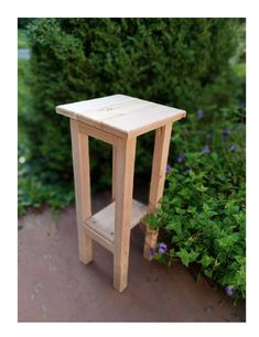 a small wooden table sitting next to some bushes