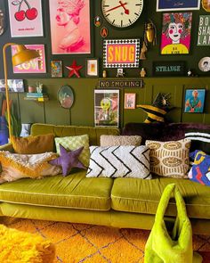 a green couch with many pillows and pictures on the wall