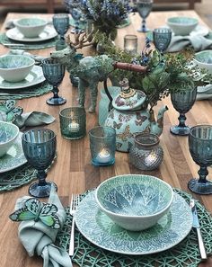 the table is set with blue dishes and place settings