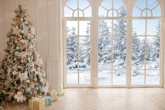 a decorated christmas tree sitting in front of an open window with snow covered trees outside