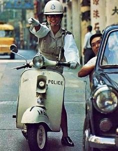 a police officer riding on the back of a scooter next to a car