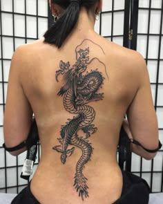 the back of a woman's body with a dragon tattoo on her lower back