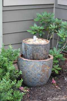 two large metal pots sitting next to each other on top of a garden planter