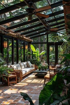 a living room filled with lots of plants and furniture under a glass roofed ceilinged area