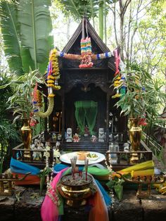 there is a small shrine in the middle of some plants and trees with decorations around it