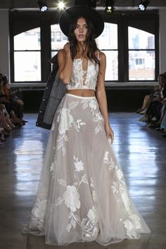 a woman in a white dress and hat walks down the runway