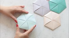 two hands are holding origami pieces on a table