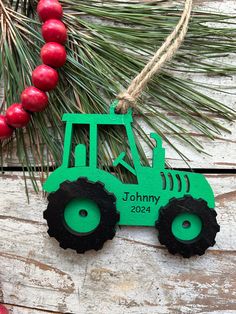 a green tractor ornament hanging from a pine tree