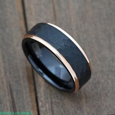 a black and gold wedding ring on top of a wooden floor