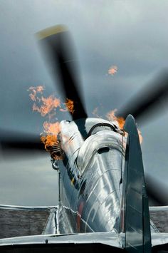 a propeller plane with flames on the wing