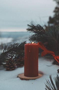 a red candle sitting on top of snow covered ground